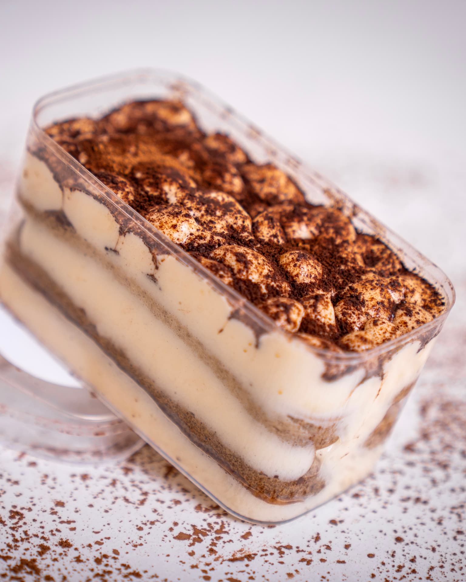 Classic Italian tiramisù dusted with cocoa in a takeaway container